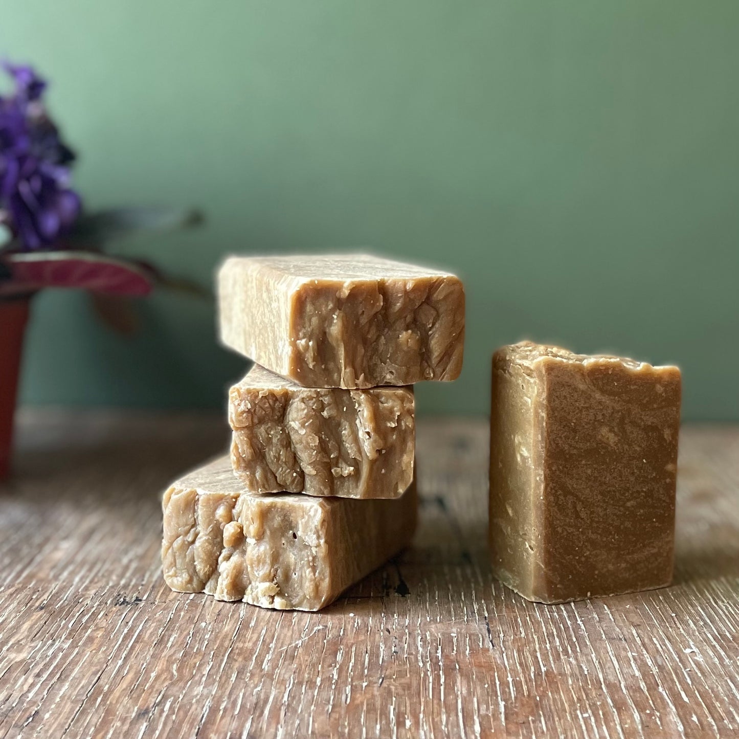 Stack of four soap bars, dark brown in color with white specks, pine tar scent.