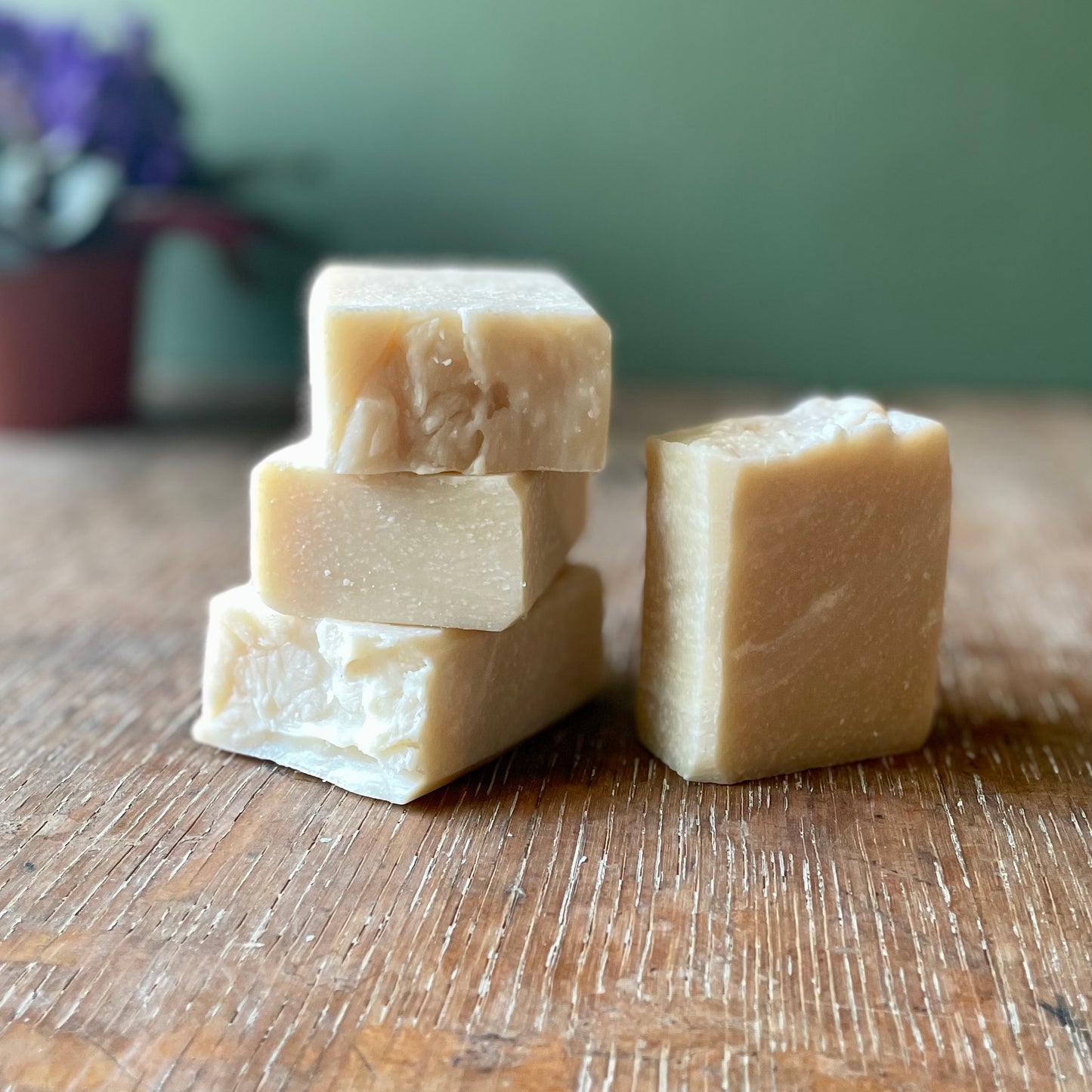 Stack of four bars of soap, off white in color with white specks, honeysuckle scent.
